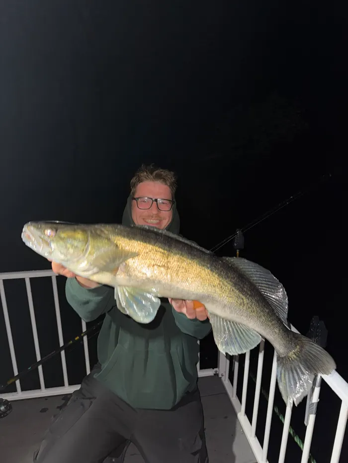 Angler mit Zander bei Nacht